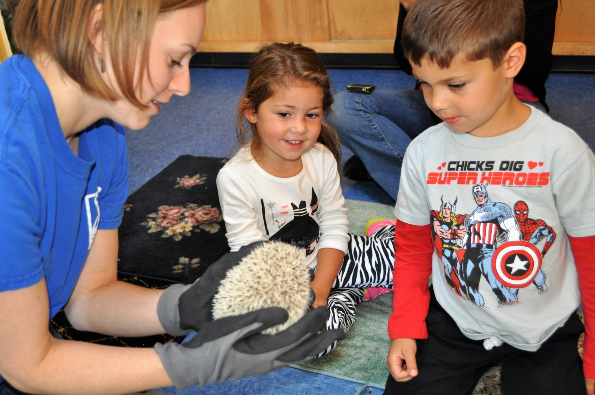 Education animal encounter - Keeper is holding hedgehog while two children observe up-close.