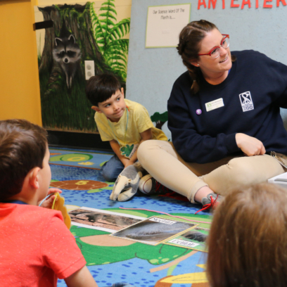 Zoo Education Staff during early childhood program showing a picture of an anteater to four children.