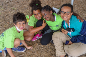 Three Zoocampers smiling and posing with Zoocamp Counselor.