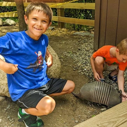 Two young boys interacting with an armadillo during an armadillo encounter.