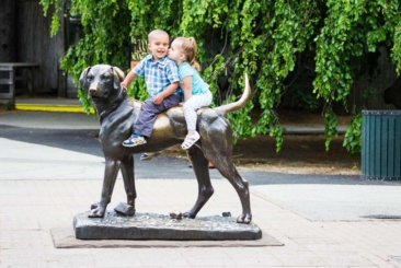 Two children sitting on top of Sentinel Dog statue at Roger Williams Zoo.