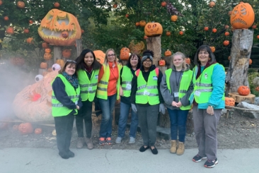 Jack-O-Lantern Spectacular volunteers smiling in front of pumpkins.