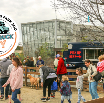 People petting goats at the Zoo, with food trucks in background.