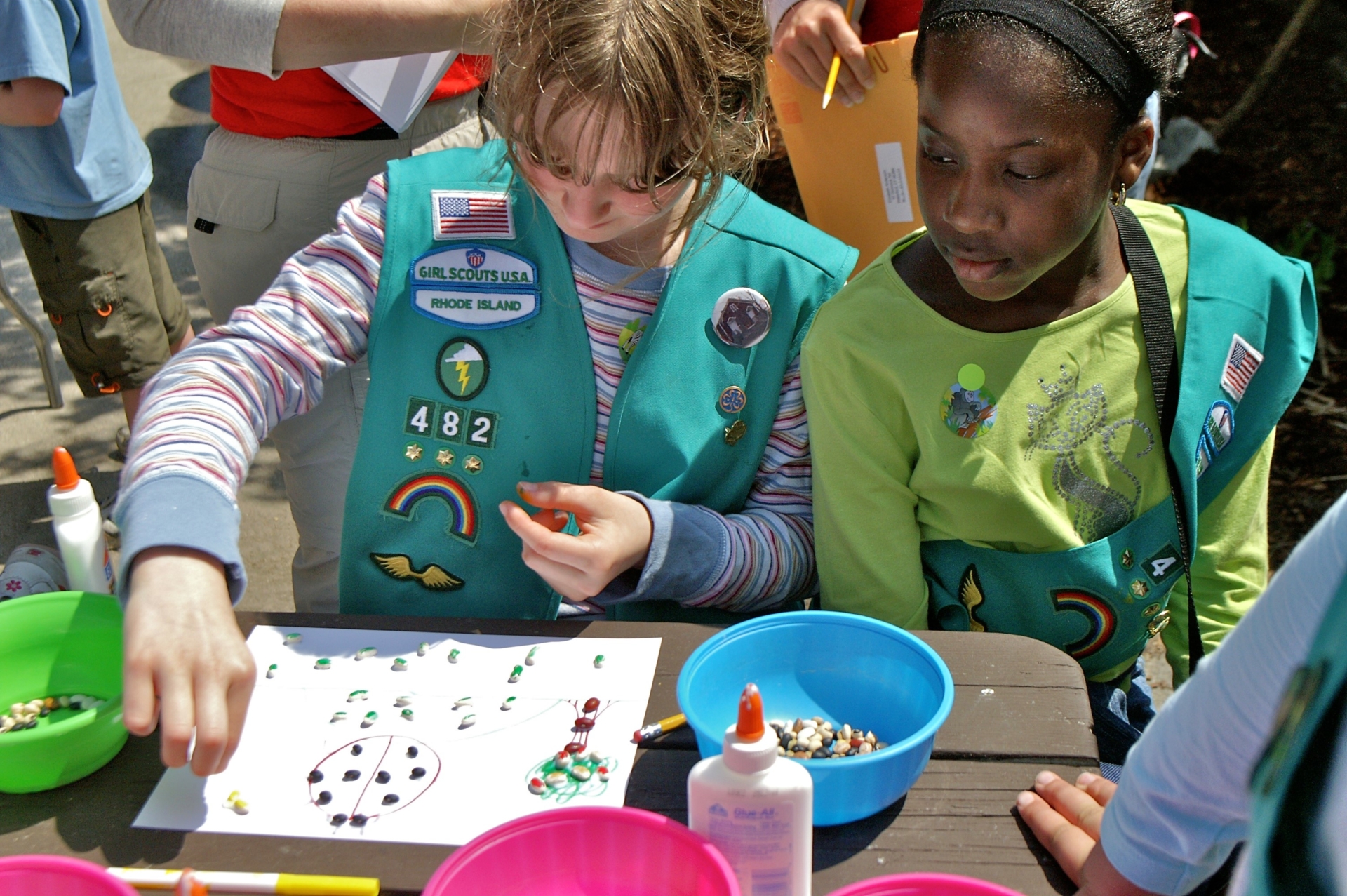 Two girl scouts sitting at a table doing crafts.