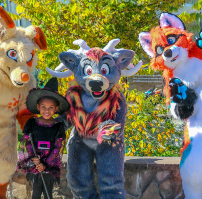 Child dressed as a witch posing with three different animal costumes at Spooky Zoo.