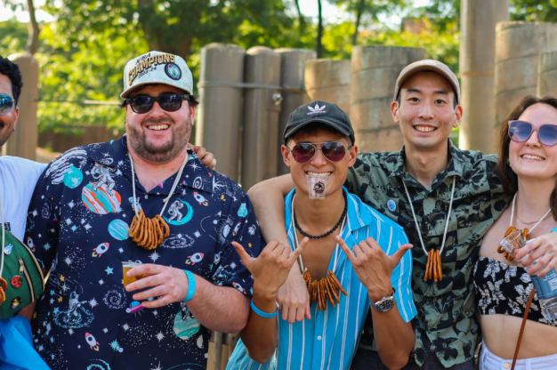 Brew at the Zoo attendees smiling and posing while wearing pretzel necklaces and holding drink tasting cups.