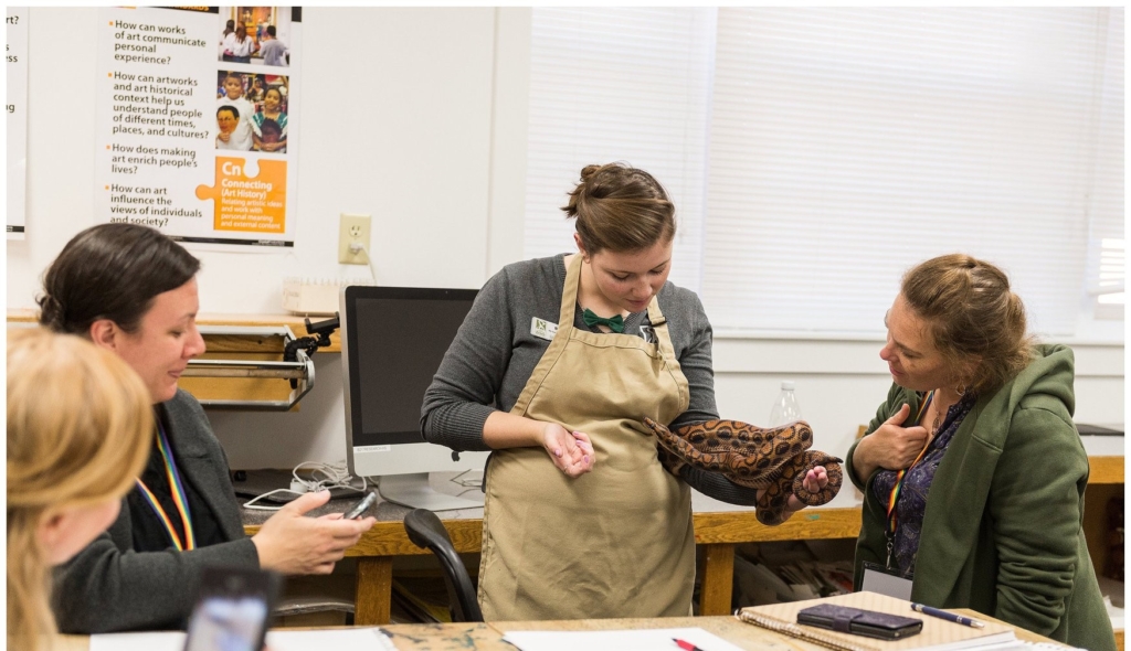 female instructor holding a snake to a class