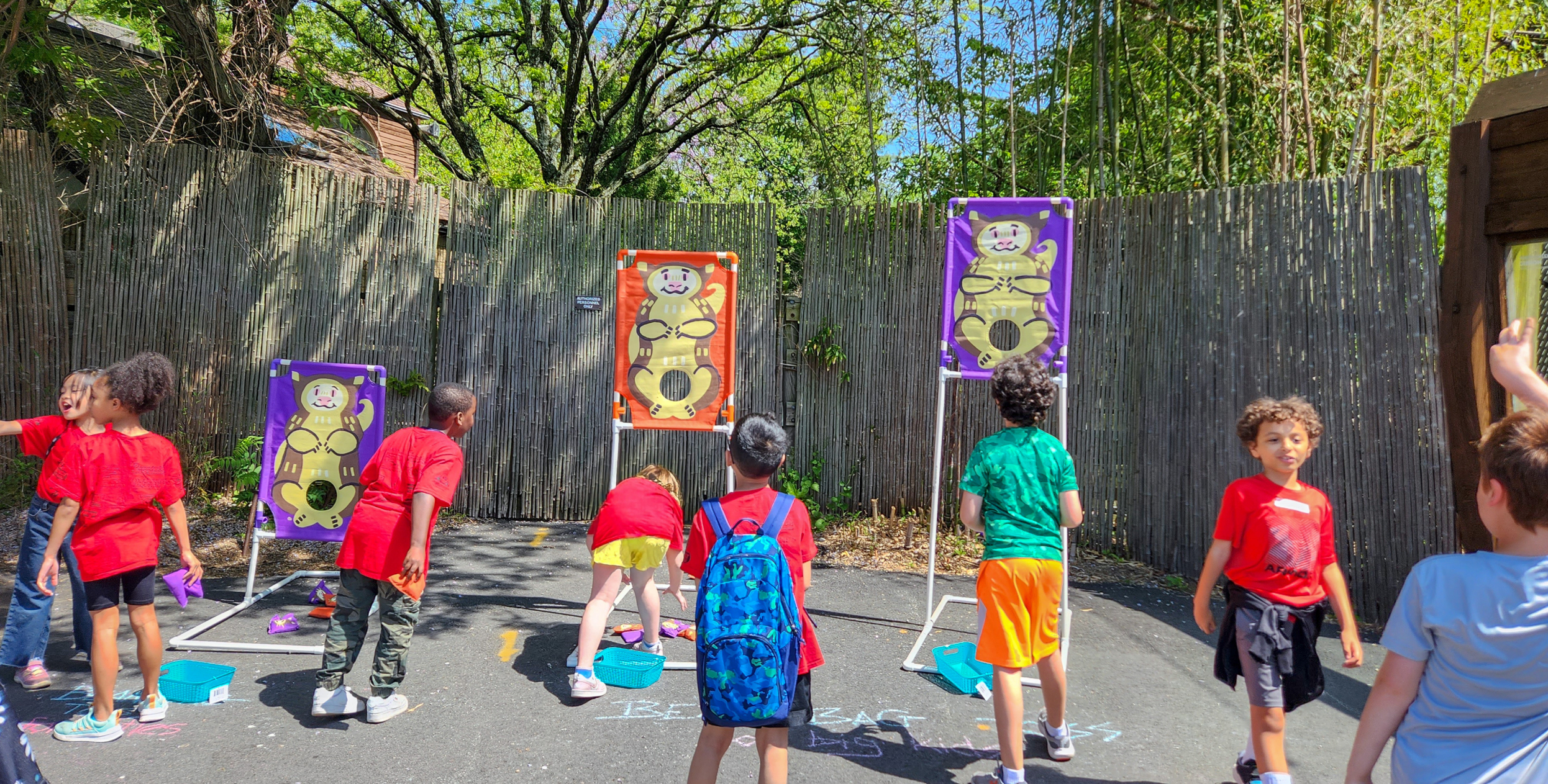 young children playing toss with tree kangaroo pouch game outside